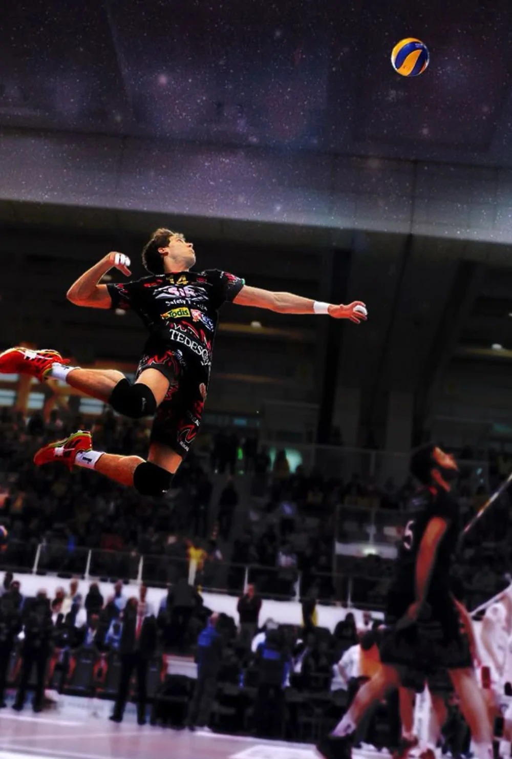 Volleyball player in mid-air performing a jump serve in a crowded arena